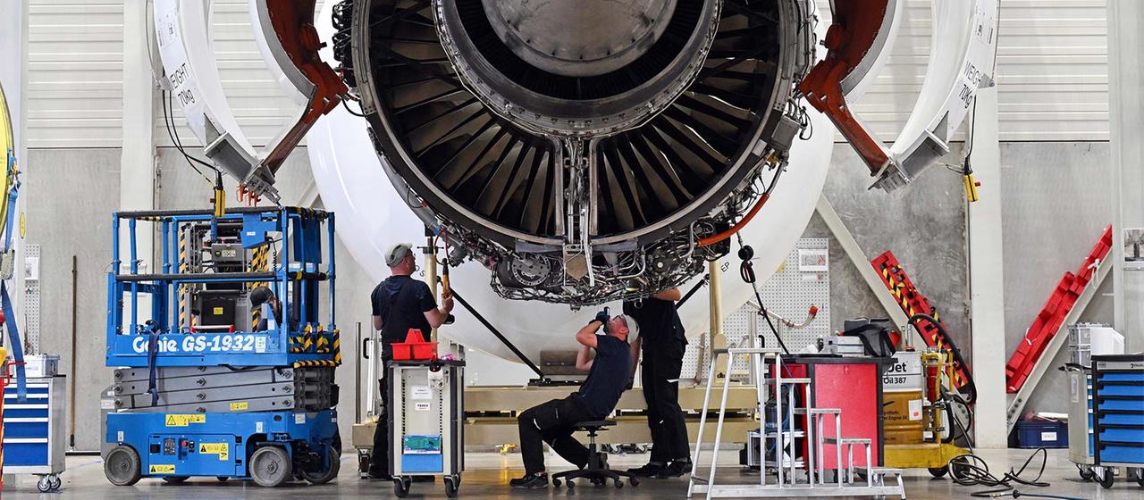 Airbus employees work on an engine for the A350 in a factory hall.