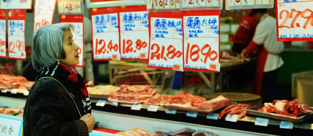 Cliente féminine entre les étiquettes de prix dans un supermarché, Hangzhou, Chine.